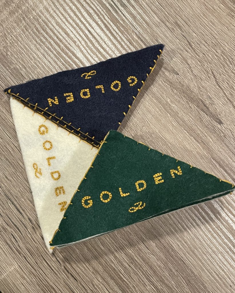 Three of my embroidered Golden bookmark in colors that match the album's versions: white, navy blue and hunter green.